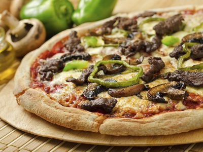 A delicious steak and mushroom pizza with green peppers and olive oil.